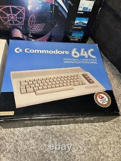 Système de test pilote Commodore 64C complet dans une grande boîte avec jeux et manuels, s'allume.