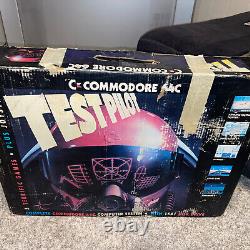 Système de test pilote Commodore 64C complet dans une grande boîte avec jeux et manuels, s'allume.